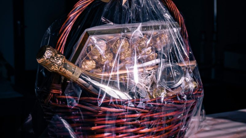 Luxurious gift basket featuring champagne and chocolates wrapped in cellophane with ribbon.